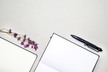 Open blank notebooks, purple flowers, pen. Business concept