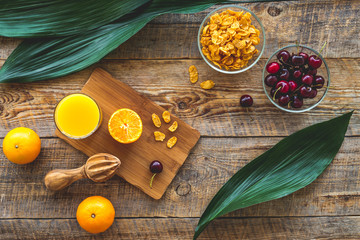 Fruits for breakfast. Oranges, cherry and muesli on wooden table background top view