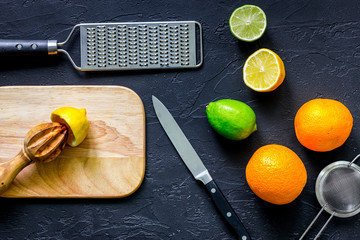 Making lemonade. Cookware and fruits on black stone background top view