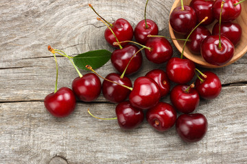 cherries in bowl on old wooden background. Top view with copy space.