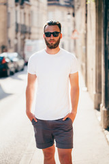 Hipster handsome male model with beard  wearing white blank  t-shirt with space for your logo or design in casual urban style