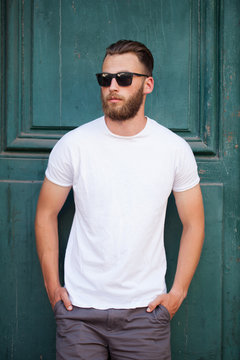Hipster handsome male model with beard  wearing white blank  t-shirt with space for your logo or design in casual urban style