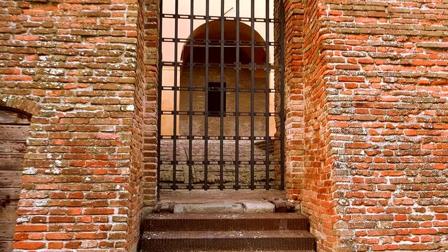 camera is going to discover the Medieval cloister behind a closed railing door, color graded clip