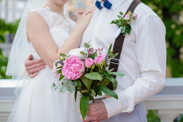 Obraz na płótnie Canvas Wedding bouquet of peonies in the hands of the newlyweds
