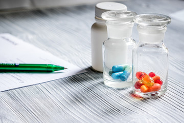 Vitamins and supplements. Pills and pill bottle on grey wooden table background