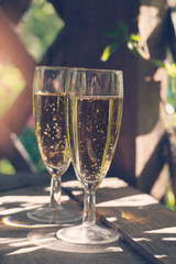 two glasses of sparkling white wine in the gazebo in the summer. matte toning.