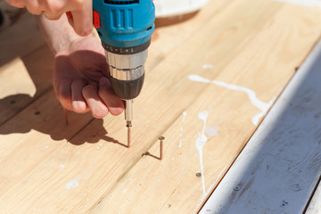 The man twists the screws into the boards using a screwdriver