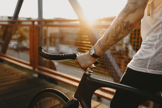 Radfahrer f&auml;hrt mit Singlespeed bei Sonnenuntergang durch die Stadt