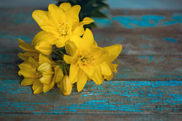 yellow lily flowers on the old weathered table
