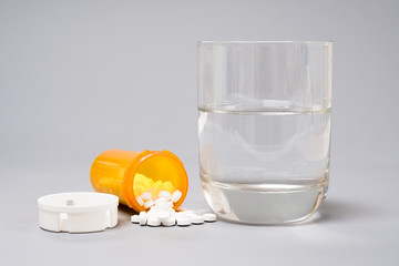 Pills and medication and a glass with water on a gray  background