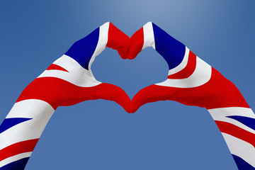 Hands flag of United Kingdom, shape a heart. Concept of country symbol, on blue sky.