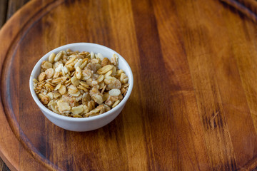 Granola or muesli in white ceramic bowl over wooden table.