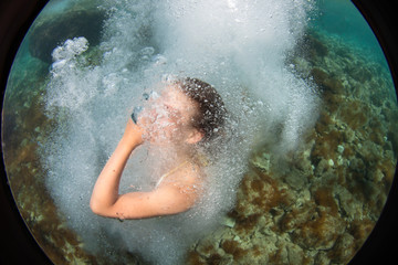 Fototapeta na wymiar Beautiful girl jumps in the sea. Fisheye lens uses to take a special effect.
