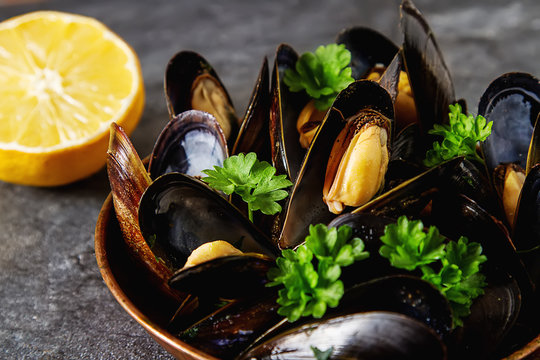 Mussels with herbs in a copper bowl. Seafood. Food at the shore of the French Sea. Dark background.
