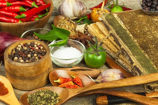 Old book of cookery recipes. Culinary background and recipe book with various spices on wooden table.