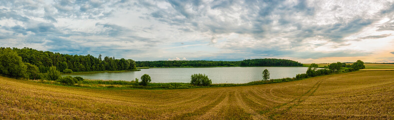 Naklejka premium Beautiful place with nice clean lake, forest and field. Sunset on summer, panoramatic view.