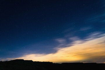 Night sky with stars next to horizon silhouette at summer