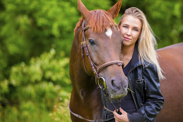 Beautiful smiling woman with her arabian horse in the field