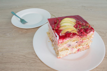 Sliced cake on wooden table background. Piece cake on white plate with fork