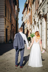 Obraz premium Young beautiful bride and groom on the wedding walk through the streets of old Rome, Italy.