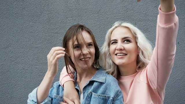Female friends taking selfie. Friends laughing and pulling faces while taking a selfie on a phone