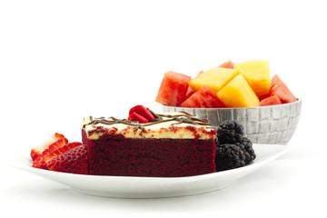 Delicious red velvet cake with berries and bowl of summer melons