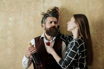 Girlfriend with glass touching messy hair of boyfriend with bottle