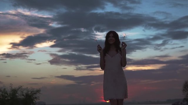 portrait of glamorous girl at sunset on a background of sky and clouds. party outdoors. slow motion