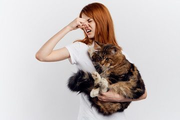 Young beautiful woman on white isolated background holds a cat, an allergy