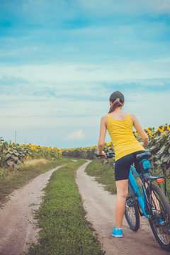 Young bicyclist riding in sunflower field