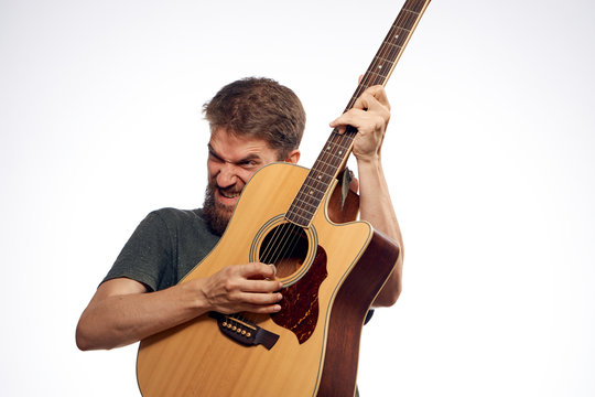 A man with a beard on a white isolated background holds a guitar, music, musical instruments, play, strings