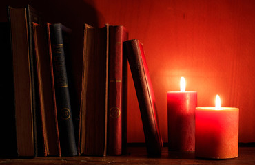 Vintage books and candles on dark background
