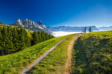 Two bikers enjoying Grosser and Kleiner Mythen surrounded by fog in Swiss Alps