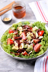 Salad from lettuce, cherry tomatoes, dried tomatoes, avocado, parmesan, pine nuts with olive oil. Healthy food.