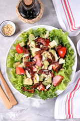 Salad from lettuce, cherry tomatoes, dried tomatoes, avocado, parmesan, pine nuts with olive oil. Healthy food.