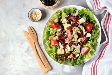 Salad from lettuce, cherry tomatoes, dried tomatoes, avocado, parmesan, pine nuts with olive oil. Healthy food.