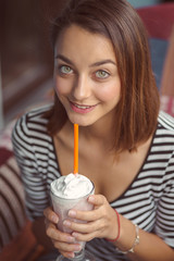 A woman sits on the summer terrace of a city cafe and drinks a milkshake