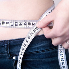 Woman measuring her waistline. The concept of diet and healthy lifestyle.