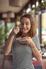 Young woman eating delicious dessert at city cafe