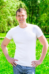 35-year-old smiling man in a T-shirt and jeans in the park