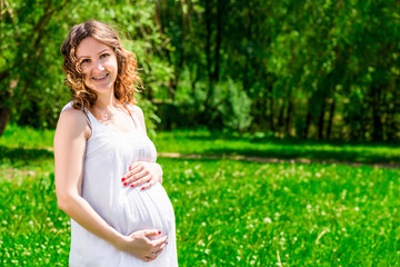 Fototapeta na wymiar Portrait of a happy future mother in anticipation of a child in a green park