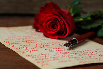 Red rose and an ink pen on a letter