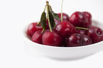Cherries in a white plate on a white background
