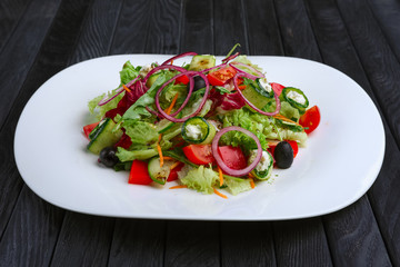 Salad with feta cheese rolled in cucumber slices with tomato and red onion