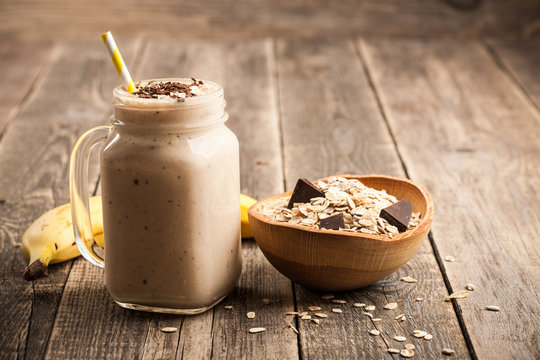 Banana chocolate smoothie and muesli on wooden table