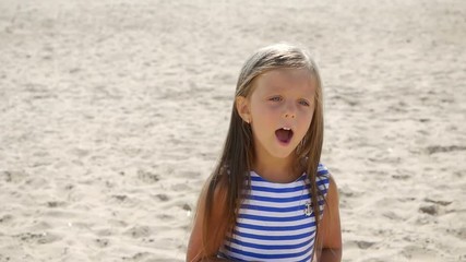 girl in a striped dress and long hair walking along the beach