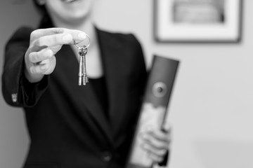 Female real estate agent smiling while handing over keys after a successful sale