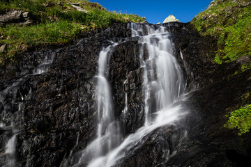 Kleiner Wasserfall im Gebirge unter blauem Himmel