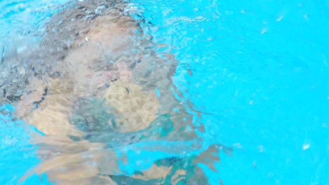 Girl dives into the pool. Bubbles in the pool.