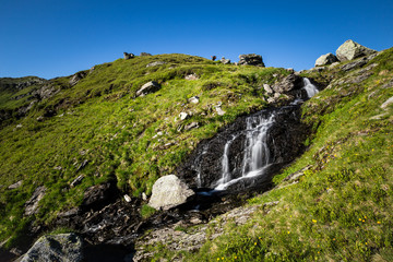 Wasser rinnt im Gebirge über kleinen Wasserfall
